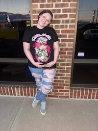 a woman wearing ripped jeans and a t - shirt